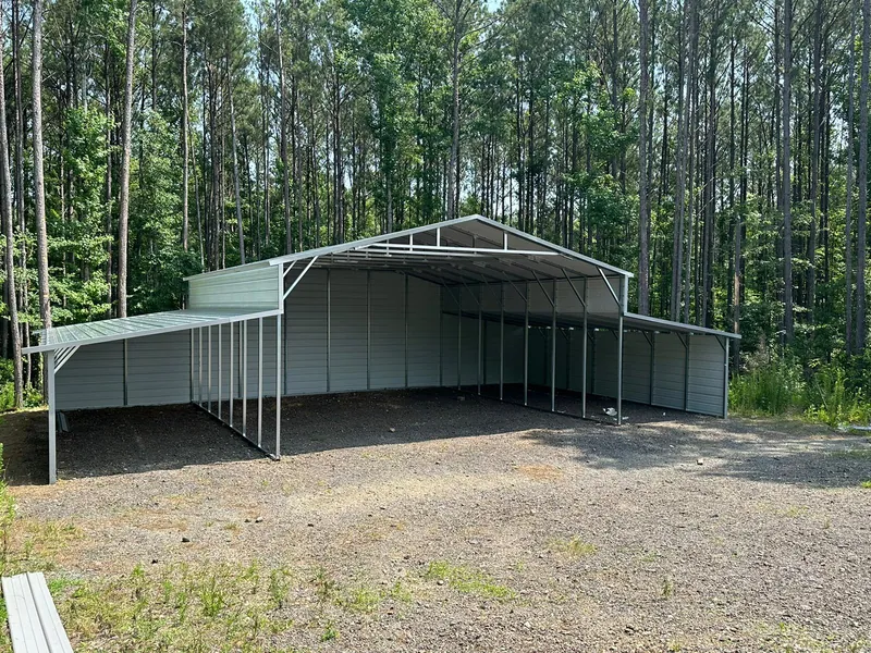 Galvalume Apex barn with open lean-to sides on a gravel lot
