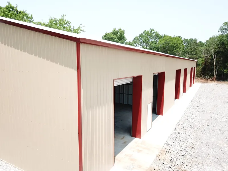 Light stone 60 by 150 foot commercial building with a row of roll-up doors along a concrete apron