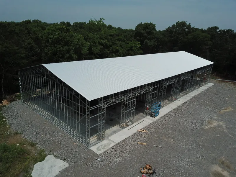 Aerial view of a 60 by 150 foot commercial building with its white roof on and walls going up