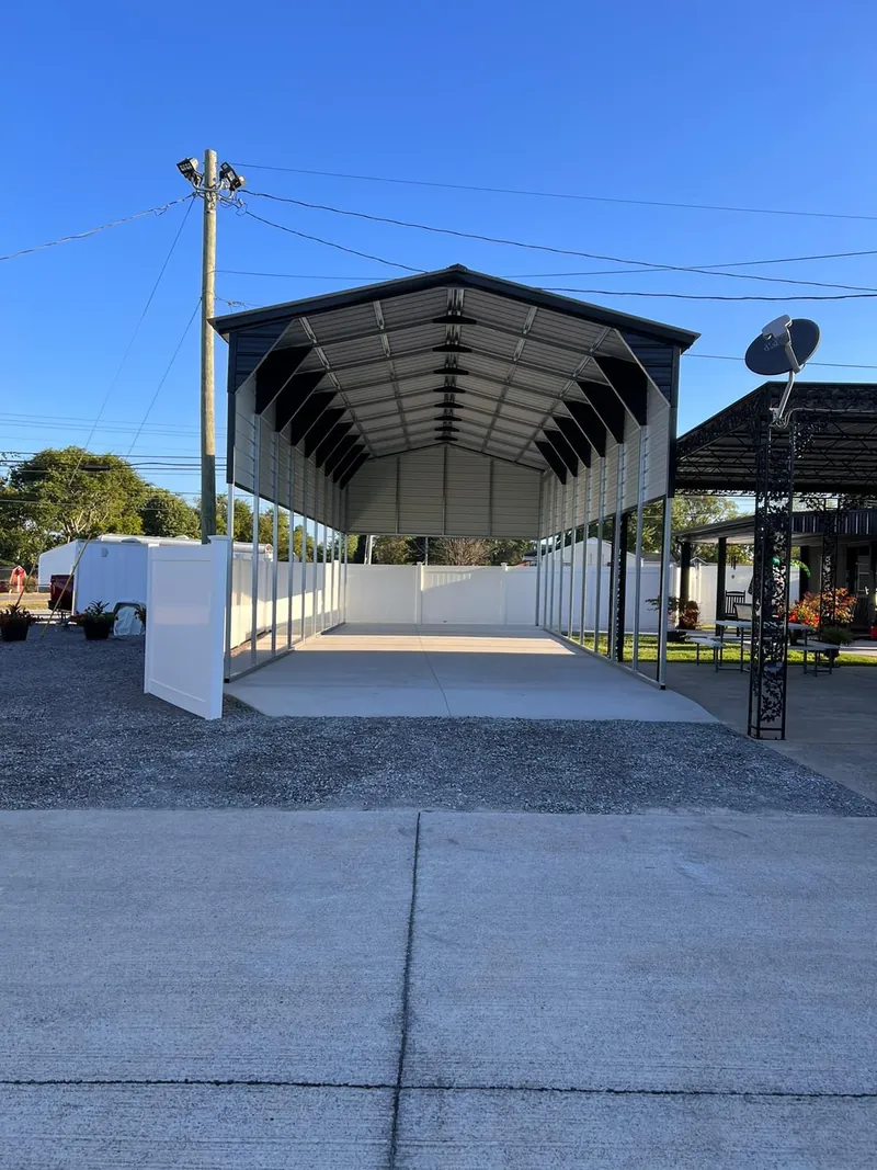 Tall black vertical-roof RV cover with a gable end panel over a concrete pad