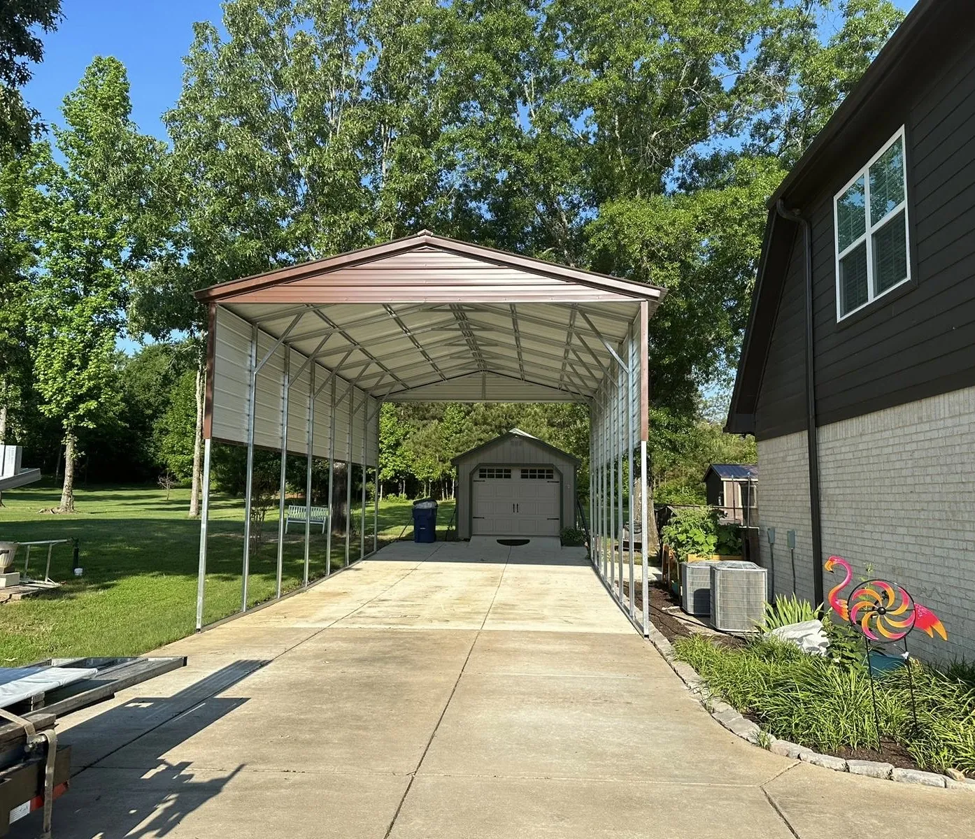 Tall brown vertical-roof RV cover over a driveway